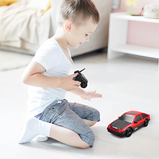 garçcon au salon avec voiture télécommandée rouge